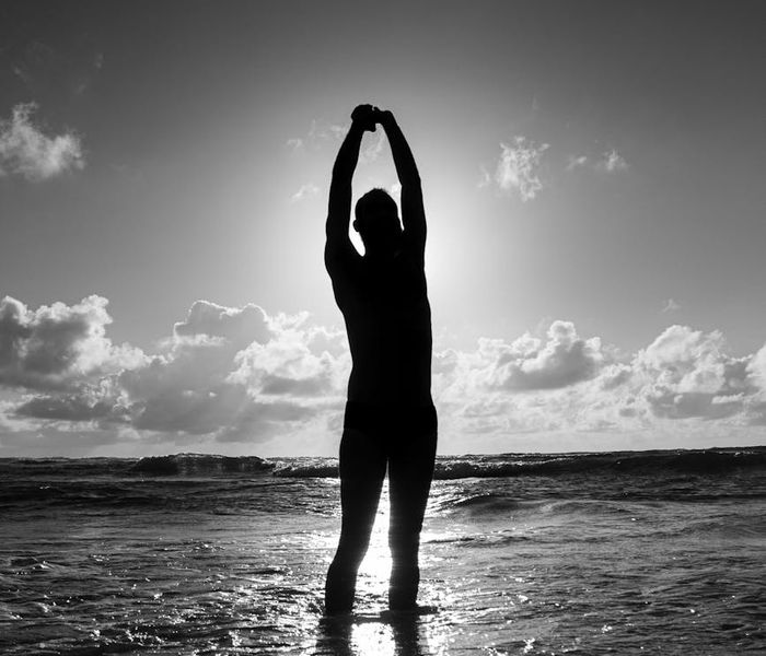 Silhouette of a man stretching against a sunrise, symbolizing energy and clarity.